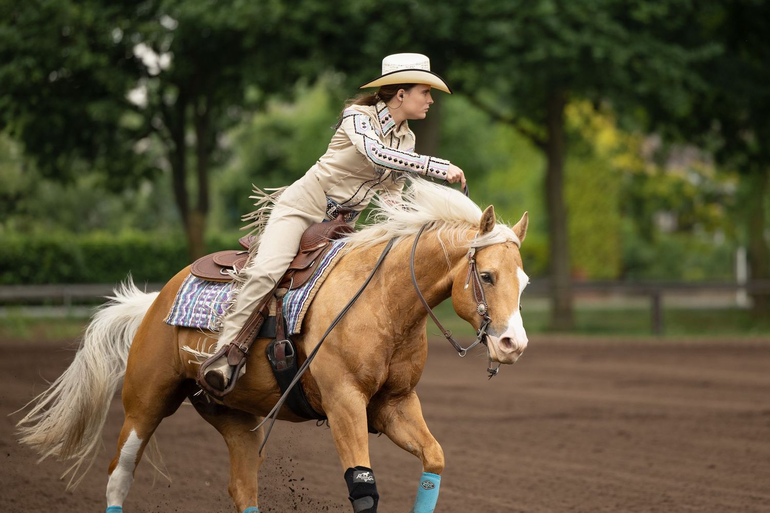Western riders practicing horsemanship patterns in outdoor dirt arena.