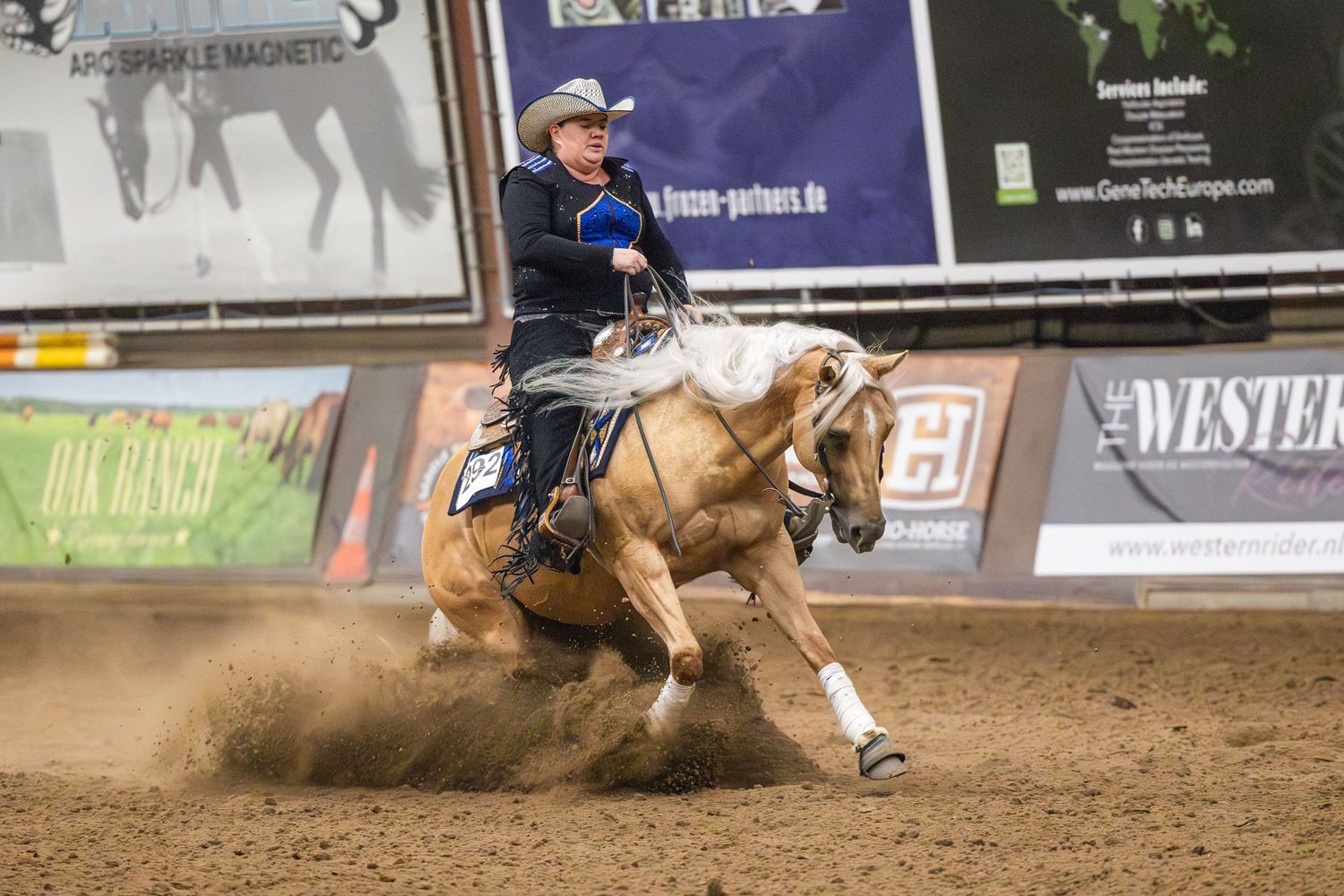 Horse and rider performing sliding stop maneuver in western reining competition.