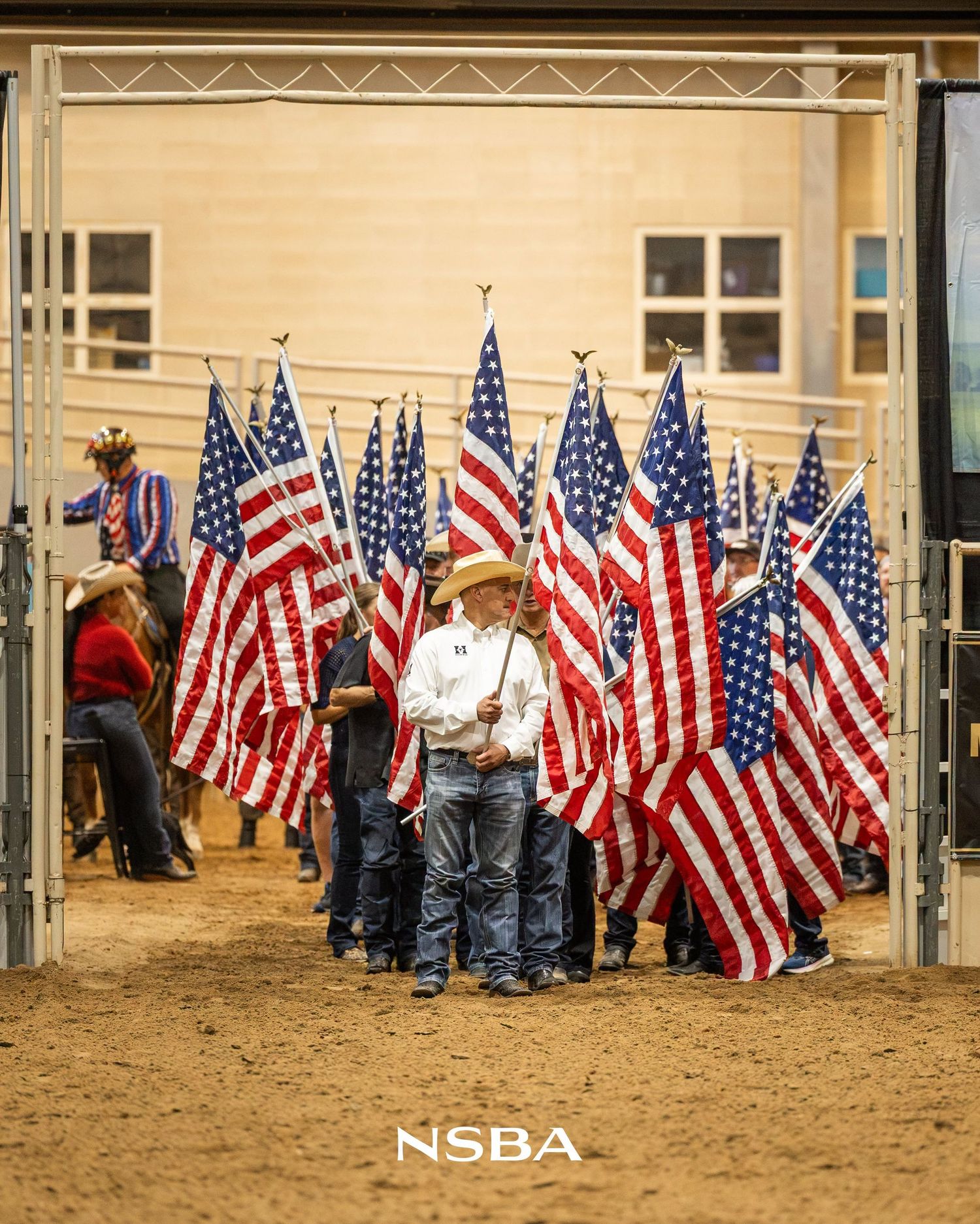 American flags the NSBA World Show during an opening ceremony on sandy ground.