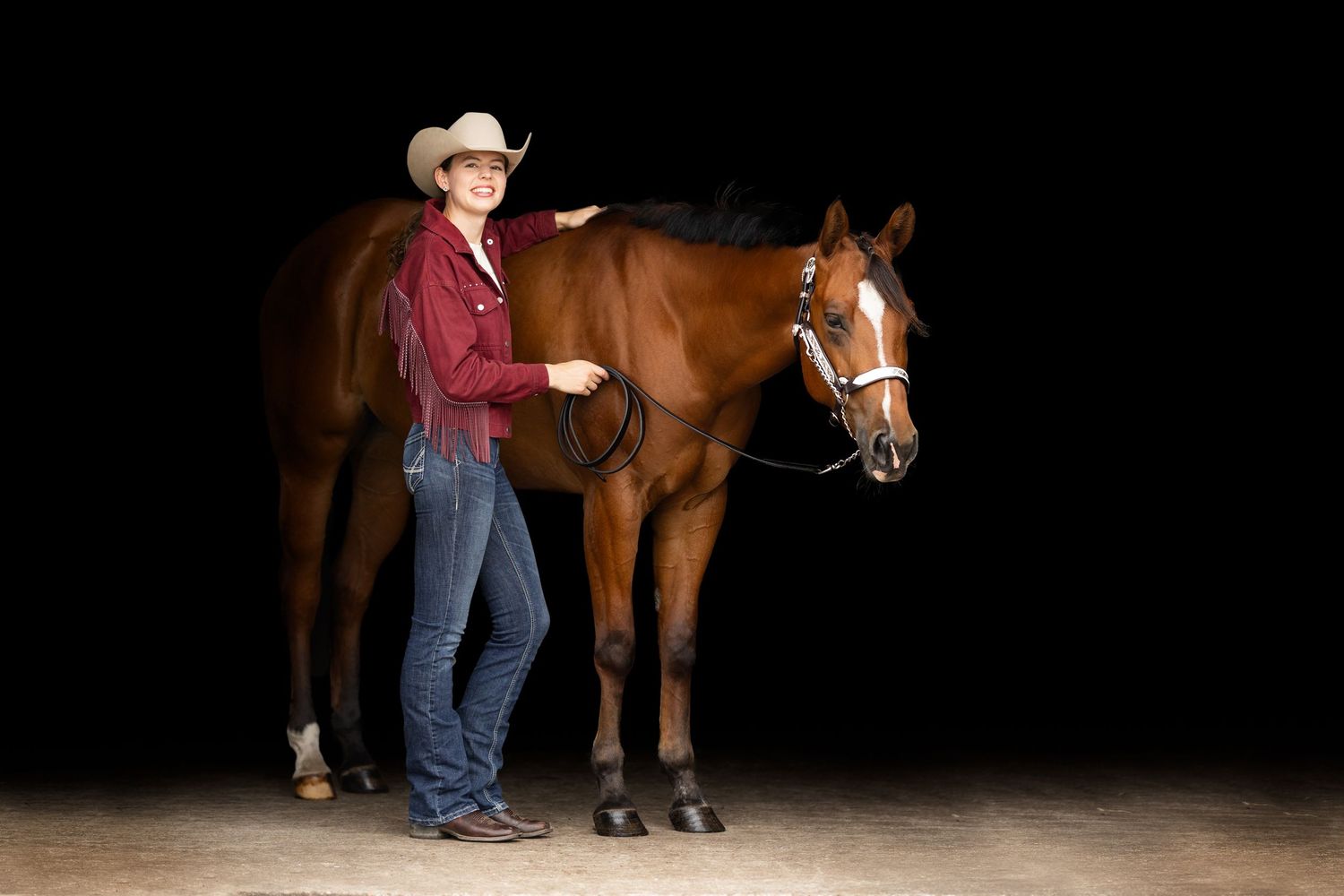 Silhouette of horse and rider against dark background with dramatic lighting.