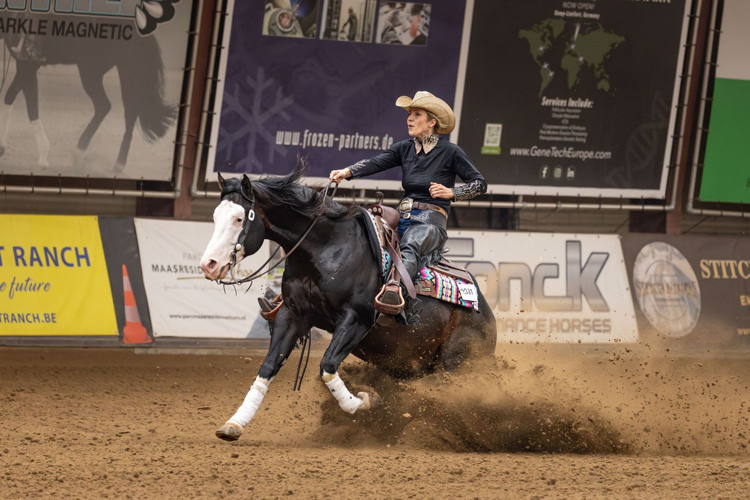 A horse and rider perform a sliding stop maneuver during a reining competition.