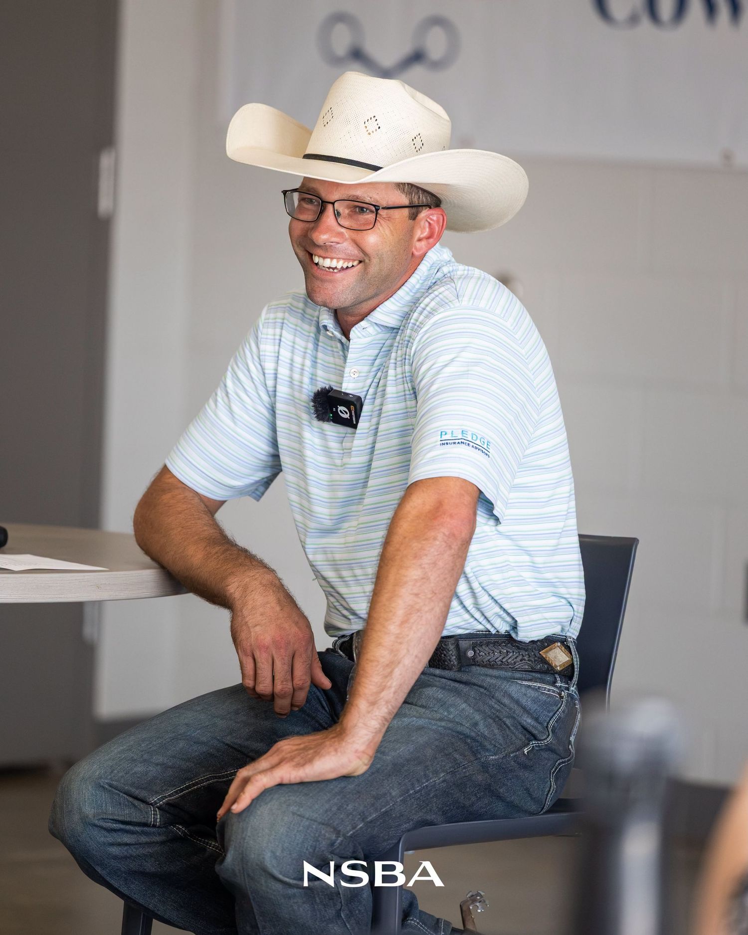 Smiling Aaron Moses wearing a white cowboy hat and striped polo shirt sitting at the NSBA World Show
