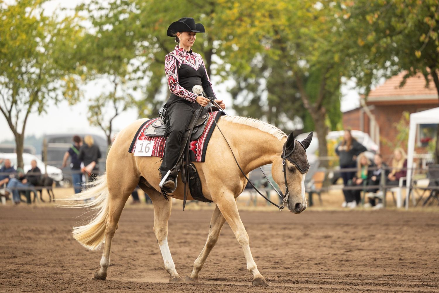A palomino horse and rider compete in a western pleasure class at a show.