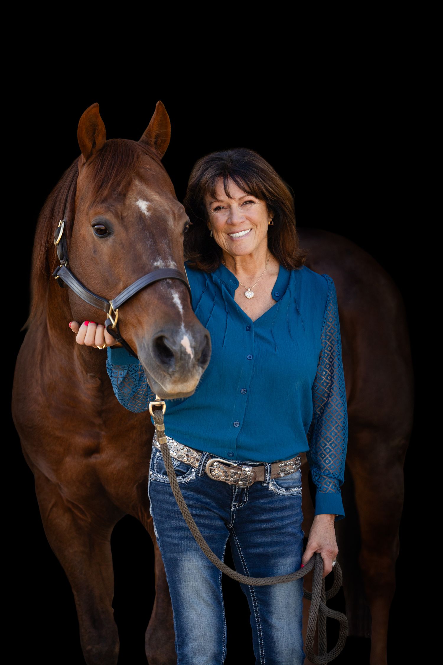 A chestnut horse and person in western wear posing together against a dark backdrop.