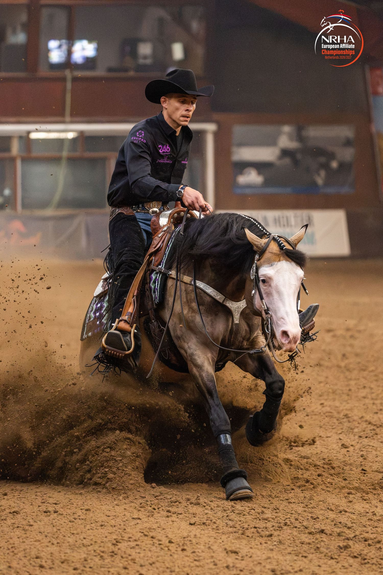 Reining horse and rider performing a sliding stop in an NRHA competition on a dirt arena floor.