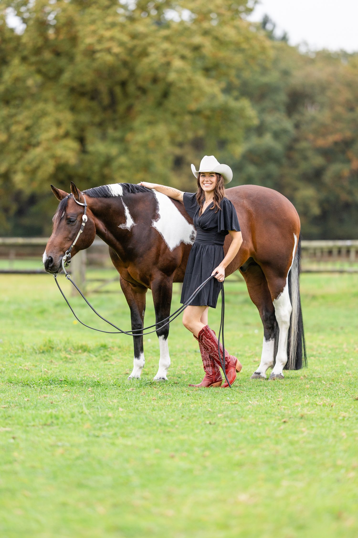 Multiple horses and handlers in grassy field during autumn photoshoot.
