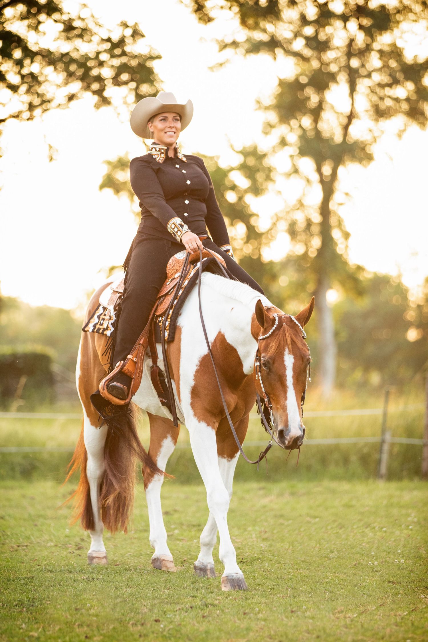 Paint horse and rider in traditional western attire during golden hour photoshoot.