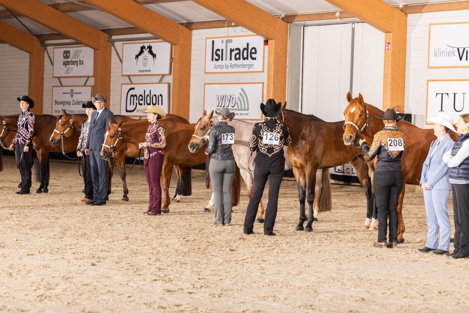 Wide view of an indoor horse arena with spectators along the walls during an event.
