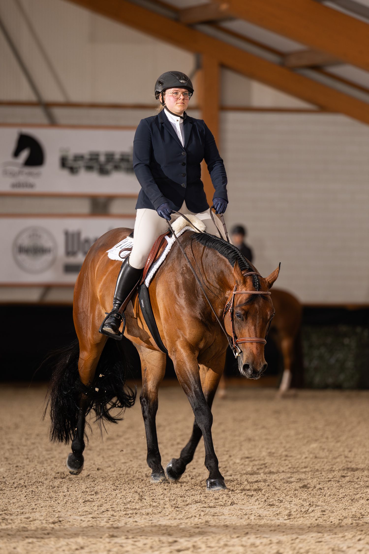 Elegant dressage performance with horse and rider in formal attire at an indoor competition.