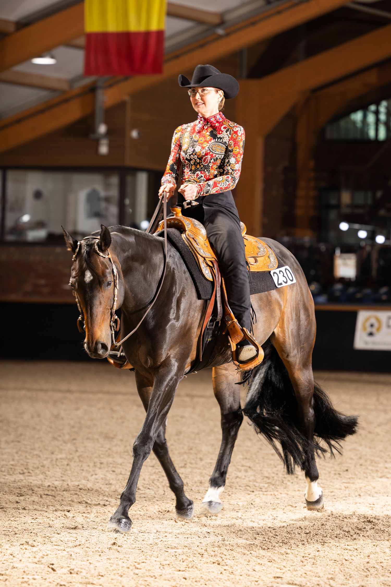 Riders performing western dressage patterns in an indoor arena setting.