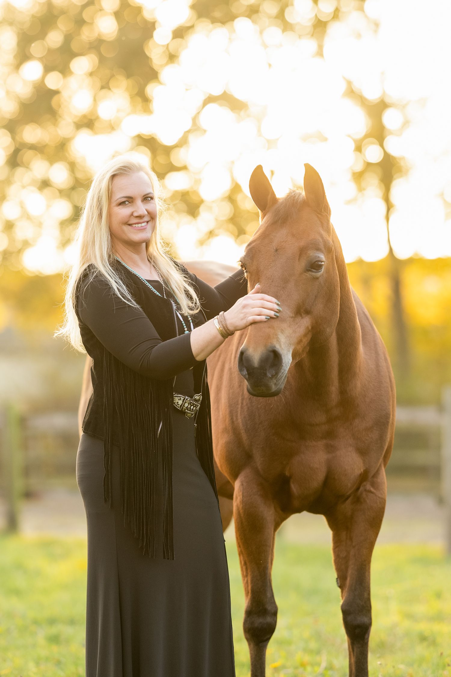 Person in black dress shares tender moment with brown Quarterhorse during sunset.