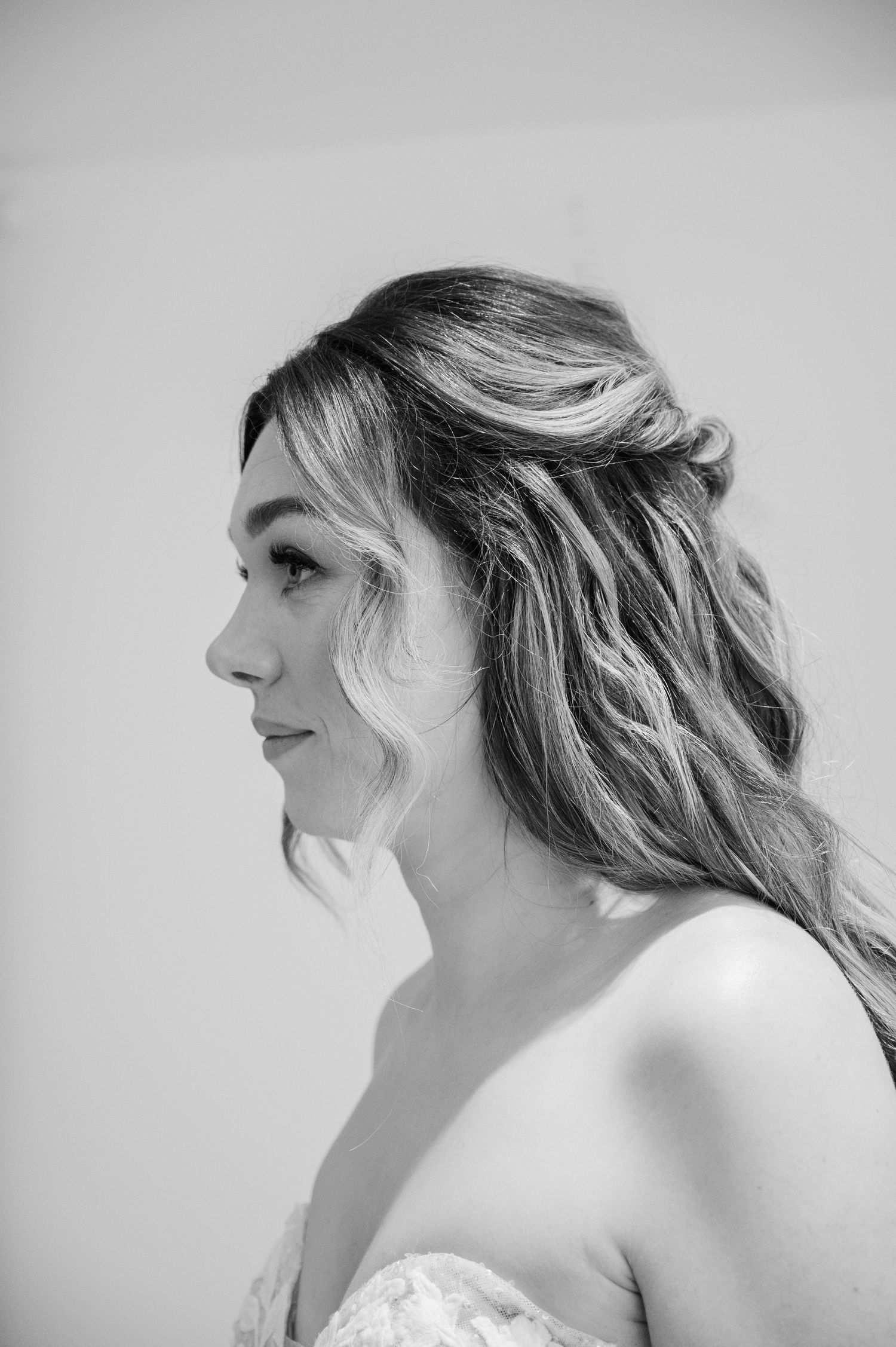 Elegant black and white profile portrait of bride with half-up wavy hairstyle on wedding day.
