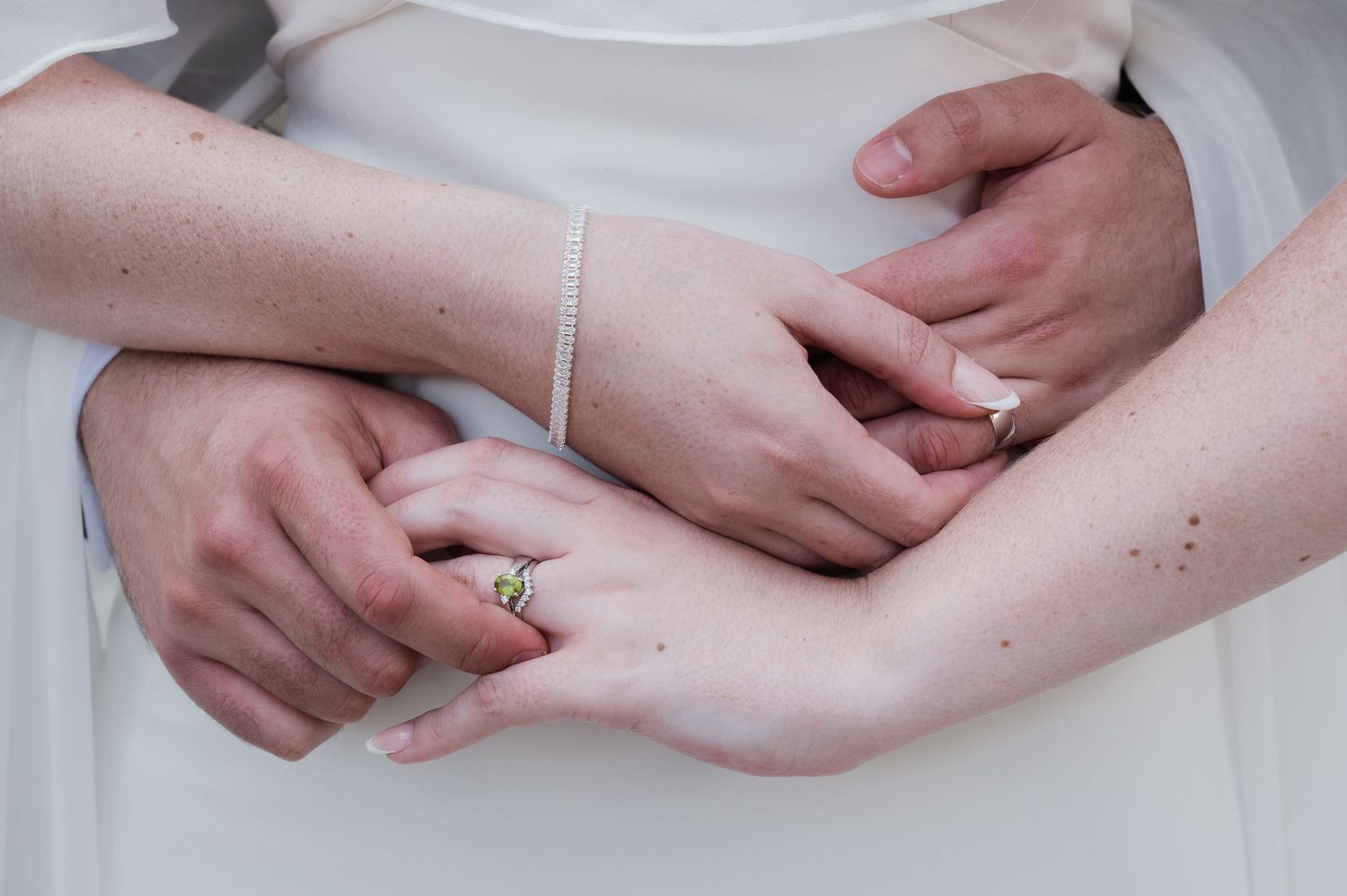 Close-up of couple's hands showing wedding rings and diamond bracelet, symbolizing love and commitment.