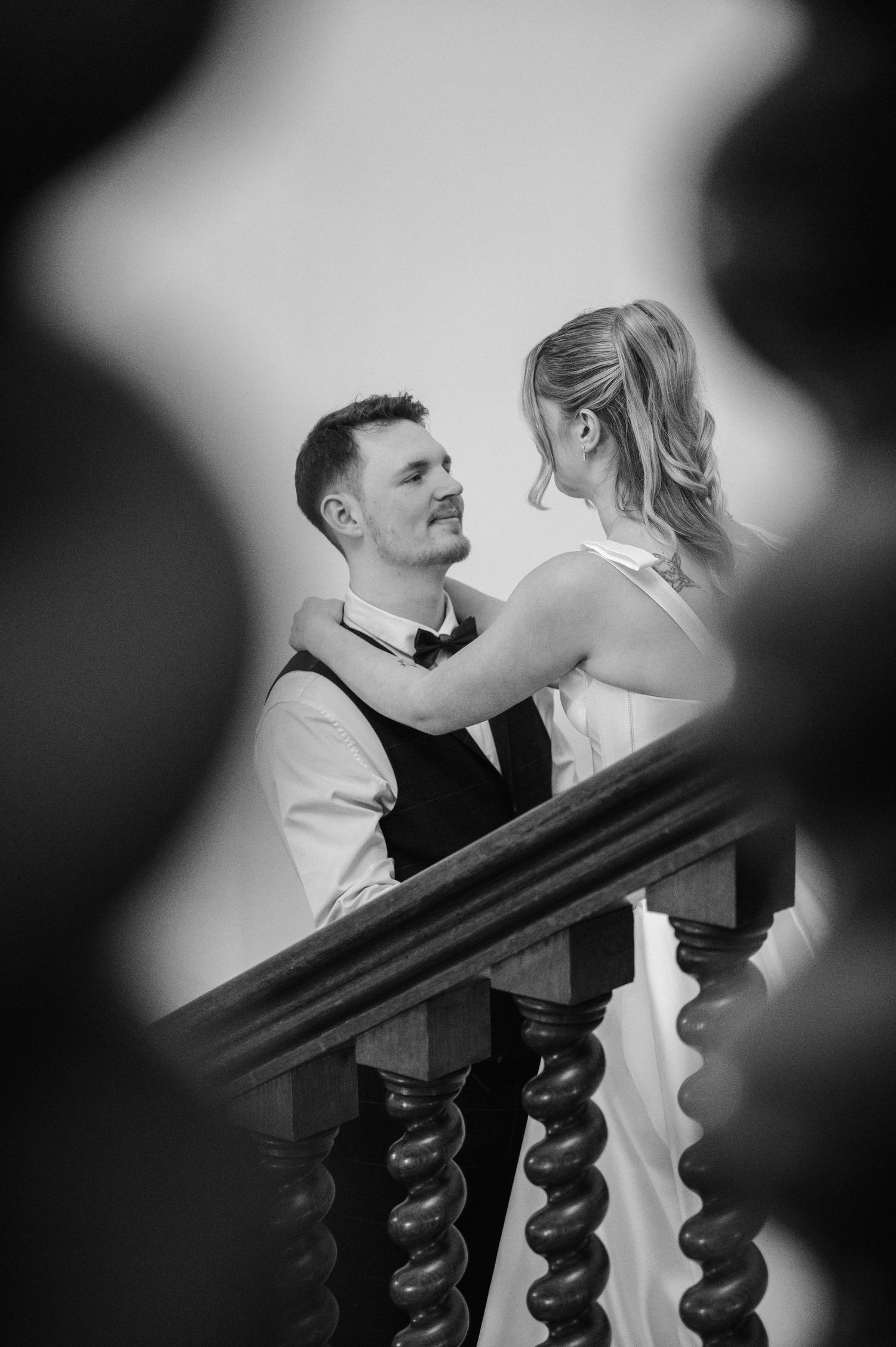 Black and white photo of bride and groom sharing an intimate moment on a staircase.