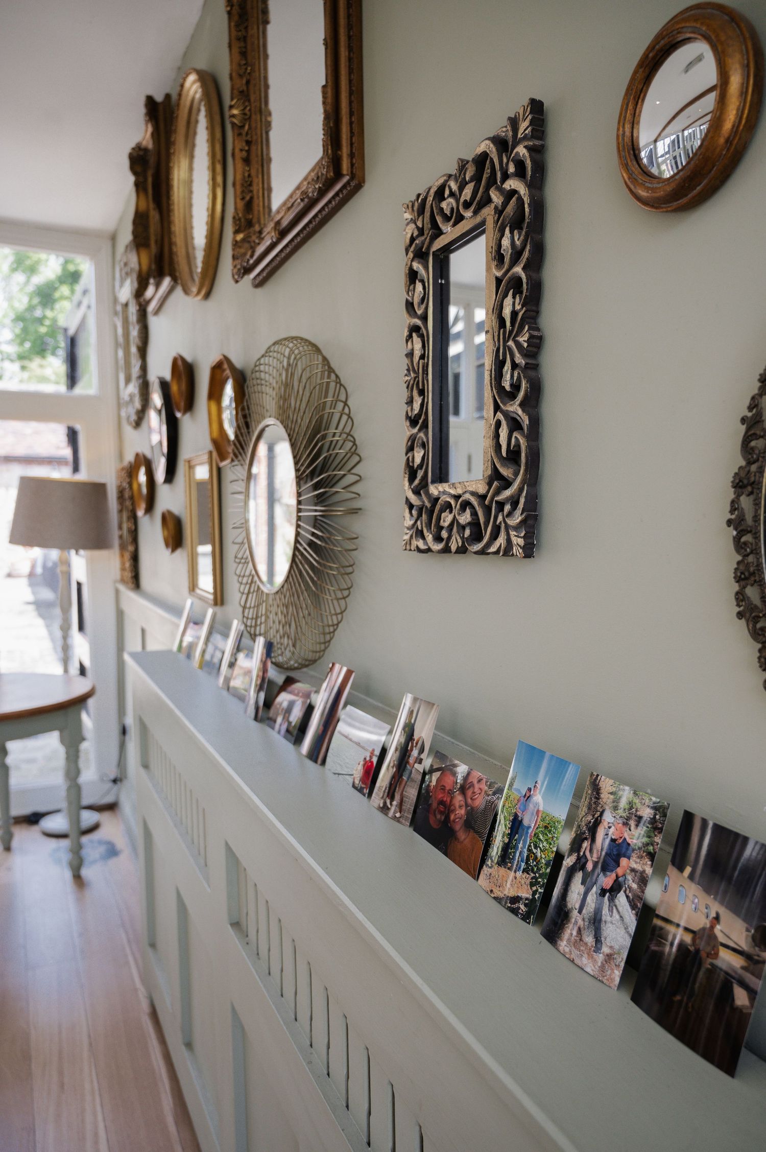 Elegant hallway with gold ornate mirrors and wedding photos displayed on a pale blue sideboard. Secret Garden