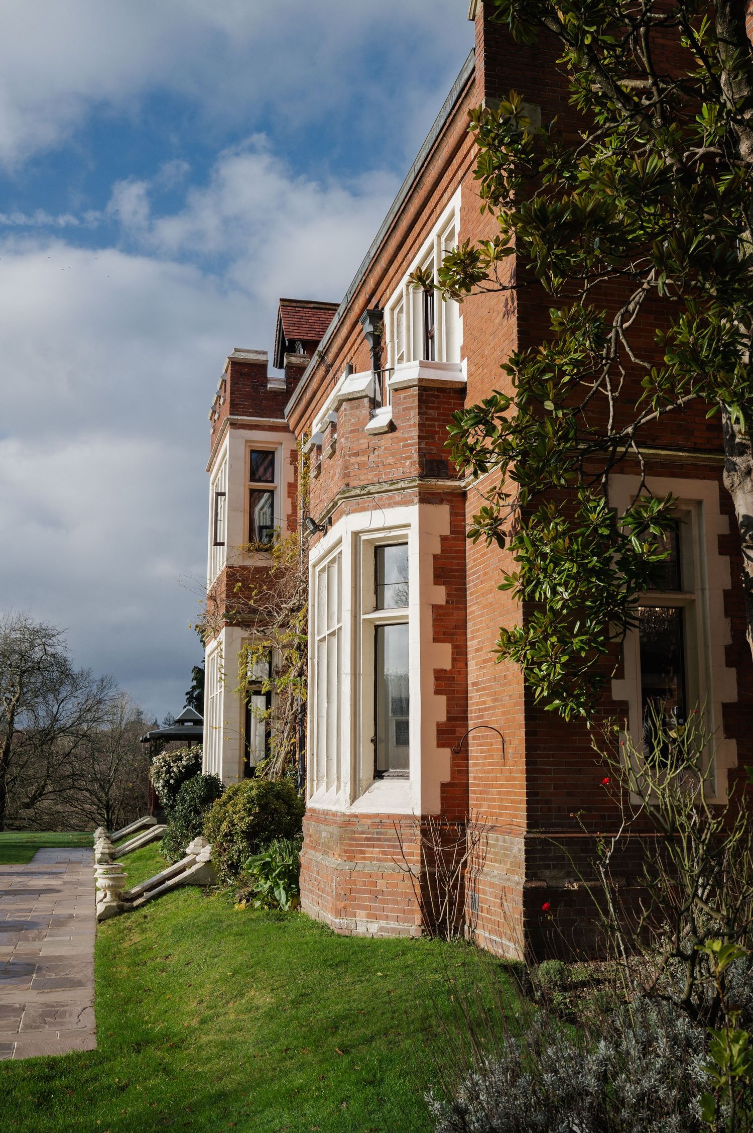 Elegant red brick Victorian wedding venue exterior with bay windows and lush greenery.