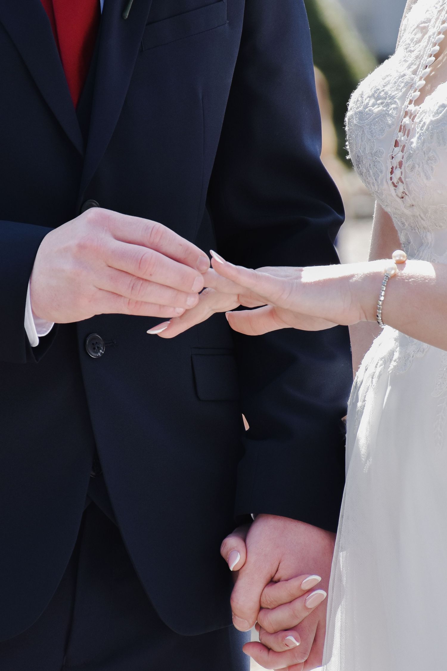 Groom placing a wedding ring on the bride's finger during the wedding ceremony.
