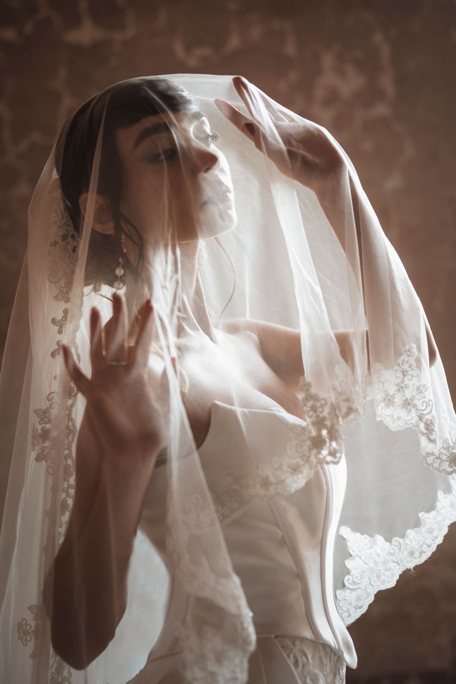 Ethereal bridal portraits through delicate white lace veil showing romantic and dreamy lighting effects.