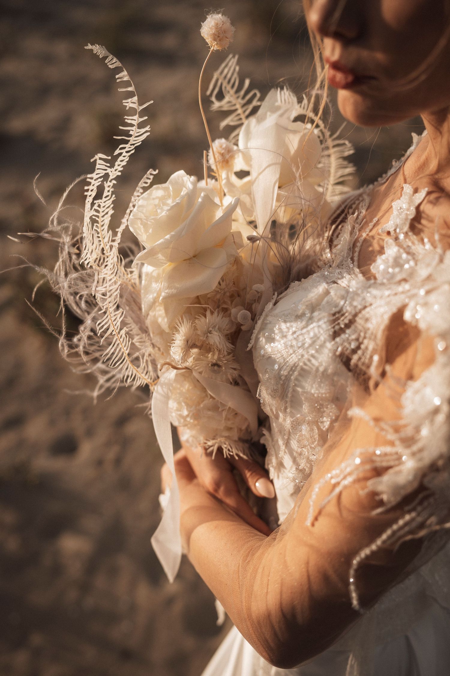 Delicate lace and feather details of a wedding dress captured in warm, intimate close-up shots.