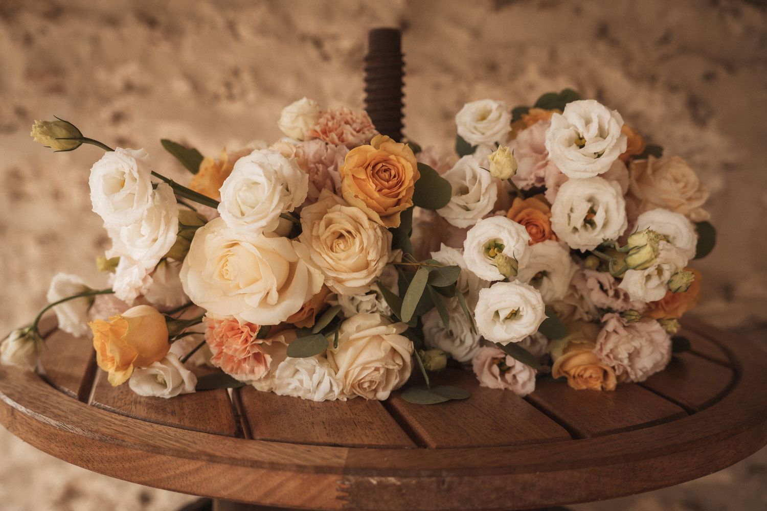 Elegant arrangement of peach and cream roses on wooden surface.
