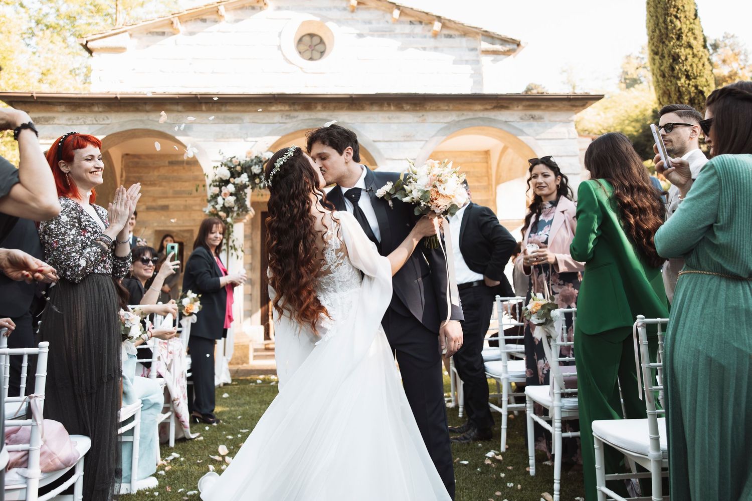 Outdoor wedding reception with guests mingling among decorated tables and chairs.