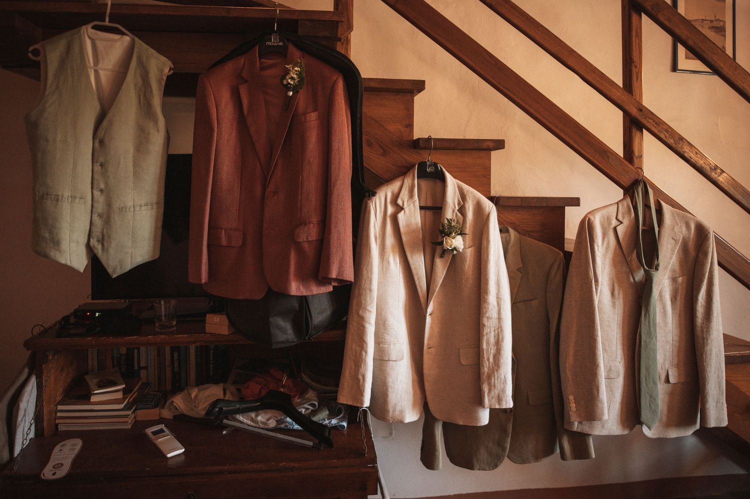 Row of formal suits and dresses hanging on wooden hangers.