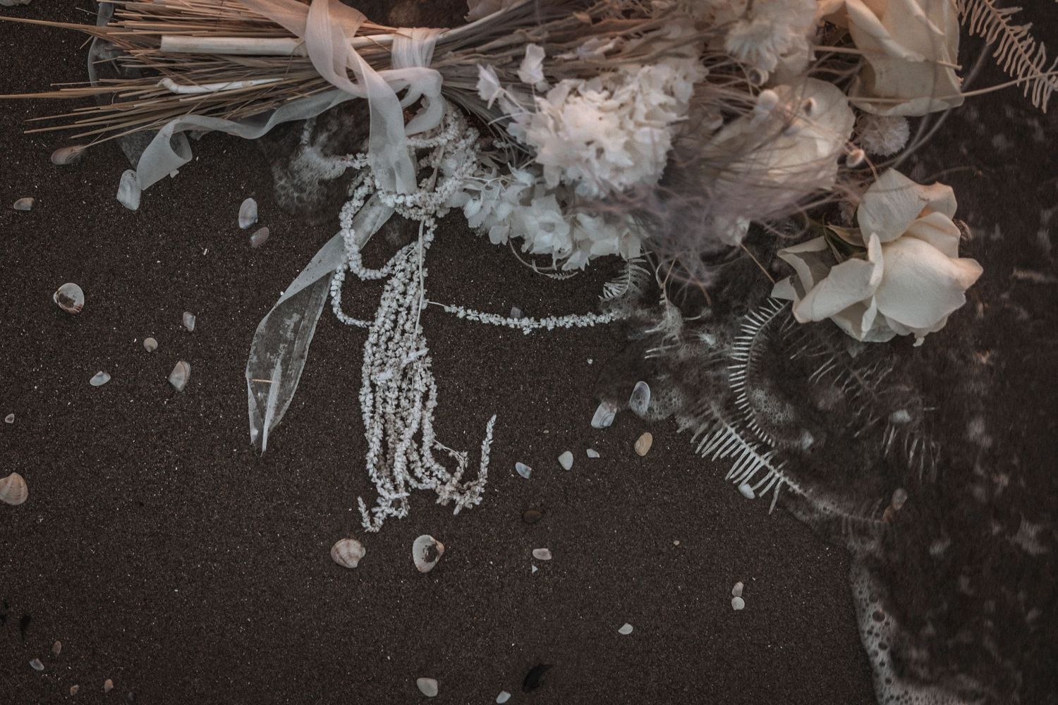 Abstract underwater-style photography of delicate lace wedding dress details in dark tones.