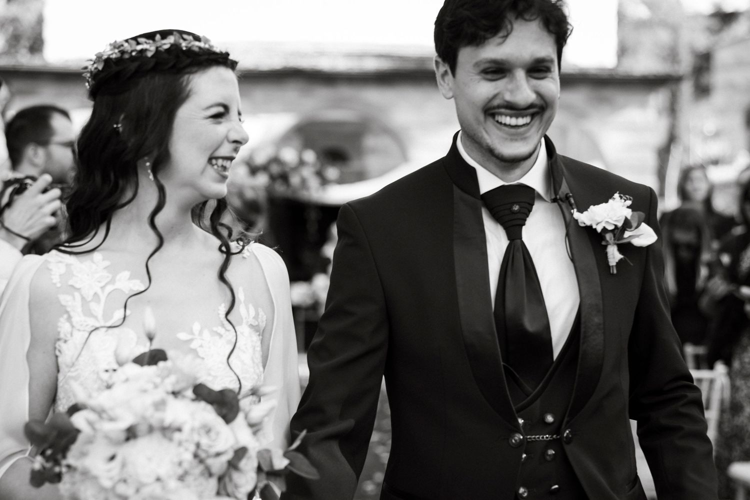 Candid wedding moment captured in black and white showing joyful laughter.