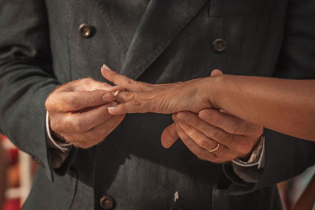 Wedding ring exchange between couple during outdoor beach ceremony.