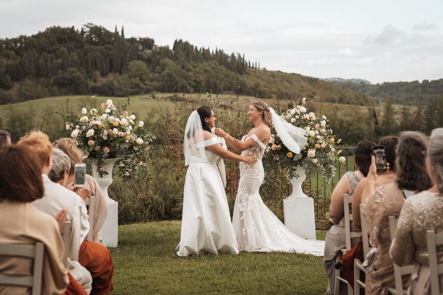 A beautiful outdoor wedding ceremony with white floral arrangements and rolling hills in the background.