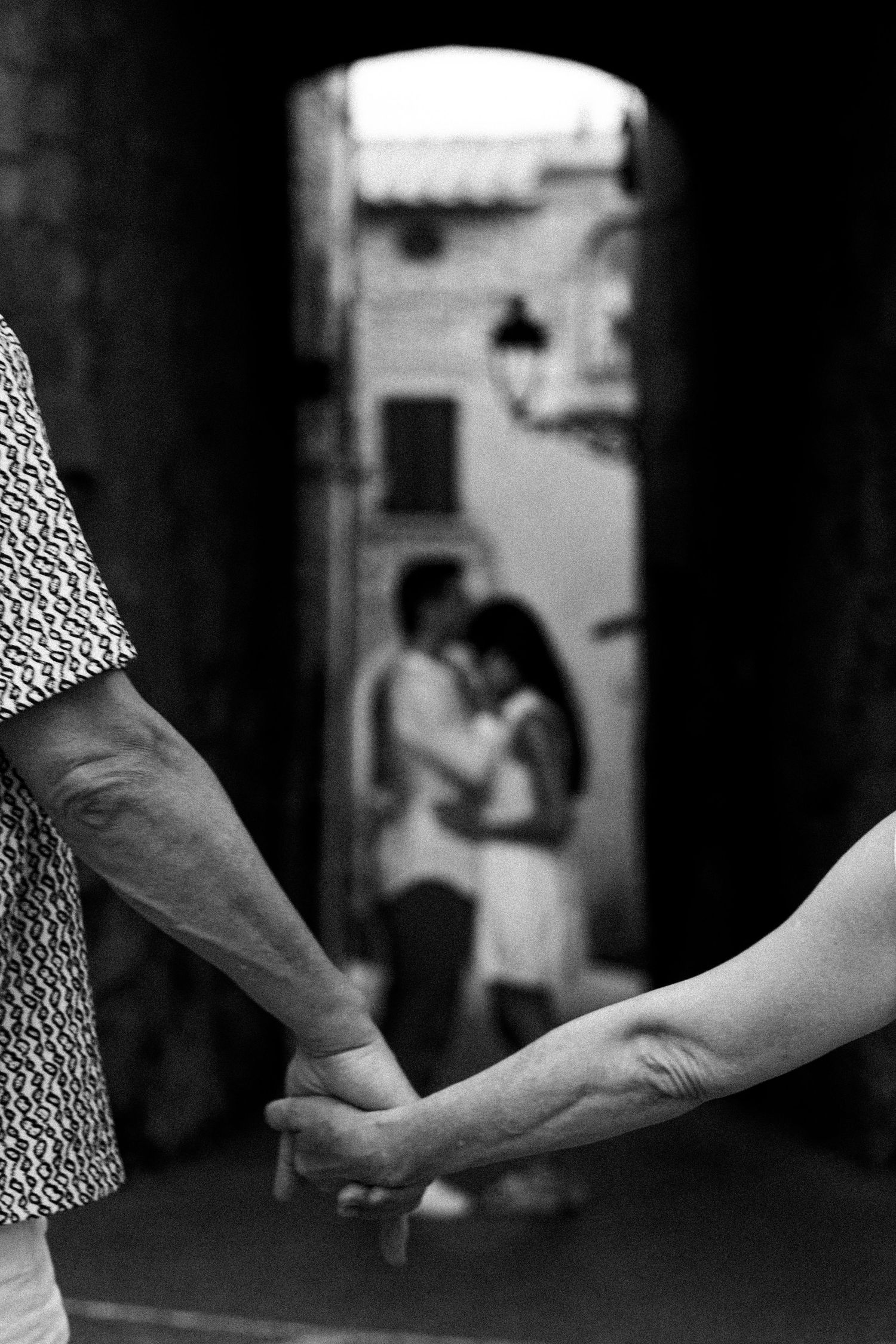 A series of black and white photographs showing hands reaching out to each other in a dark corridor.