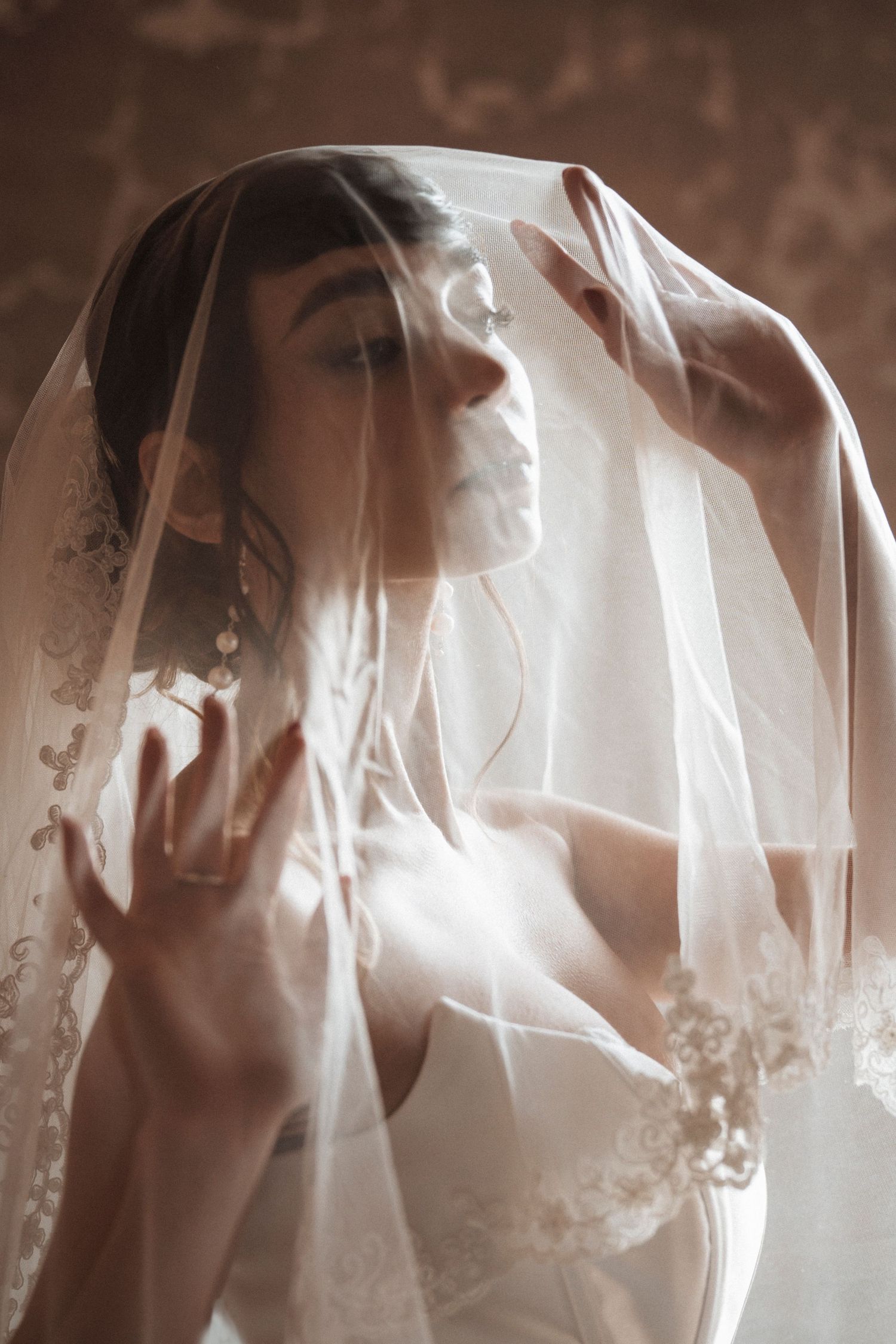 Ethereal bridal portrait with soft light filtering through delicate white veils.