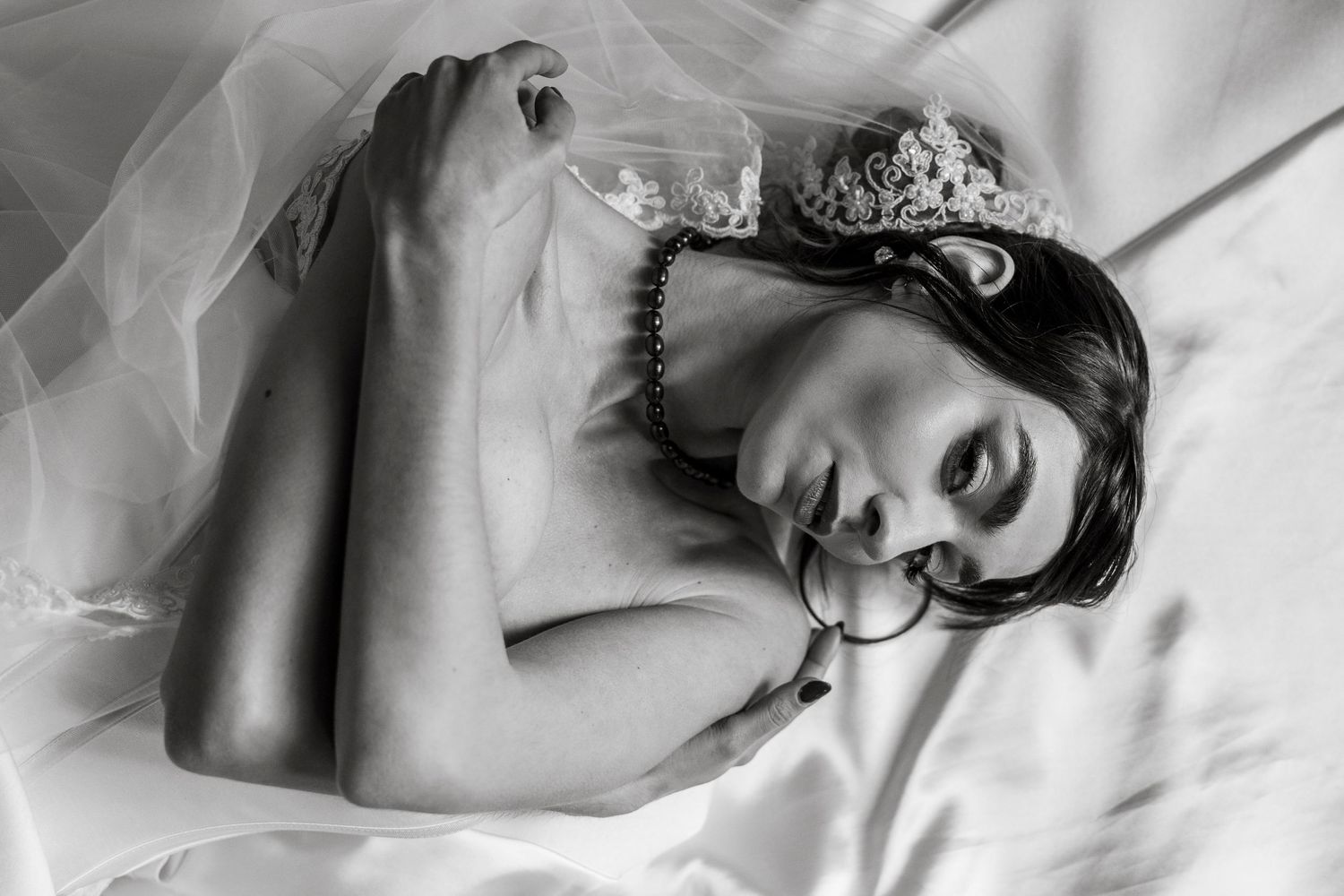 A black and white artistic portrait series showing intimate close-up shots of a person laying on white sheets.