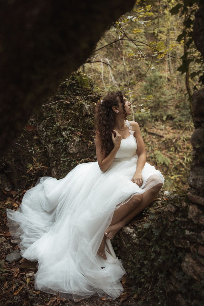 A person in a flowing white wedding dress twirls gracefully in a dreamy forest setting.