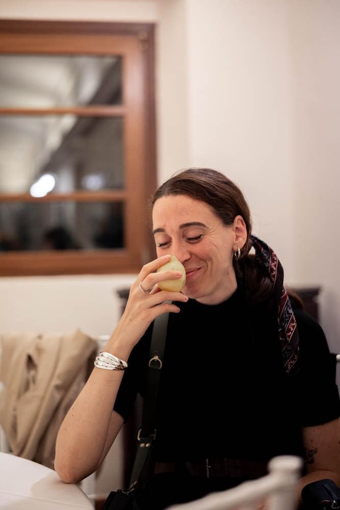 A person in a black shirt laughing while covering their face with their hands.