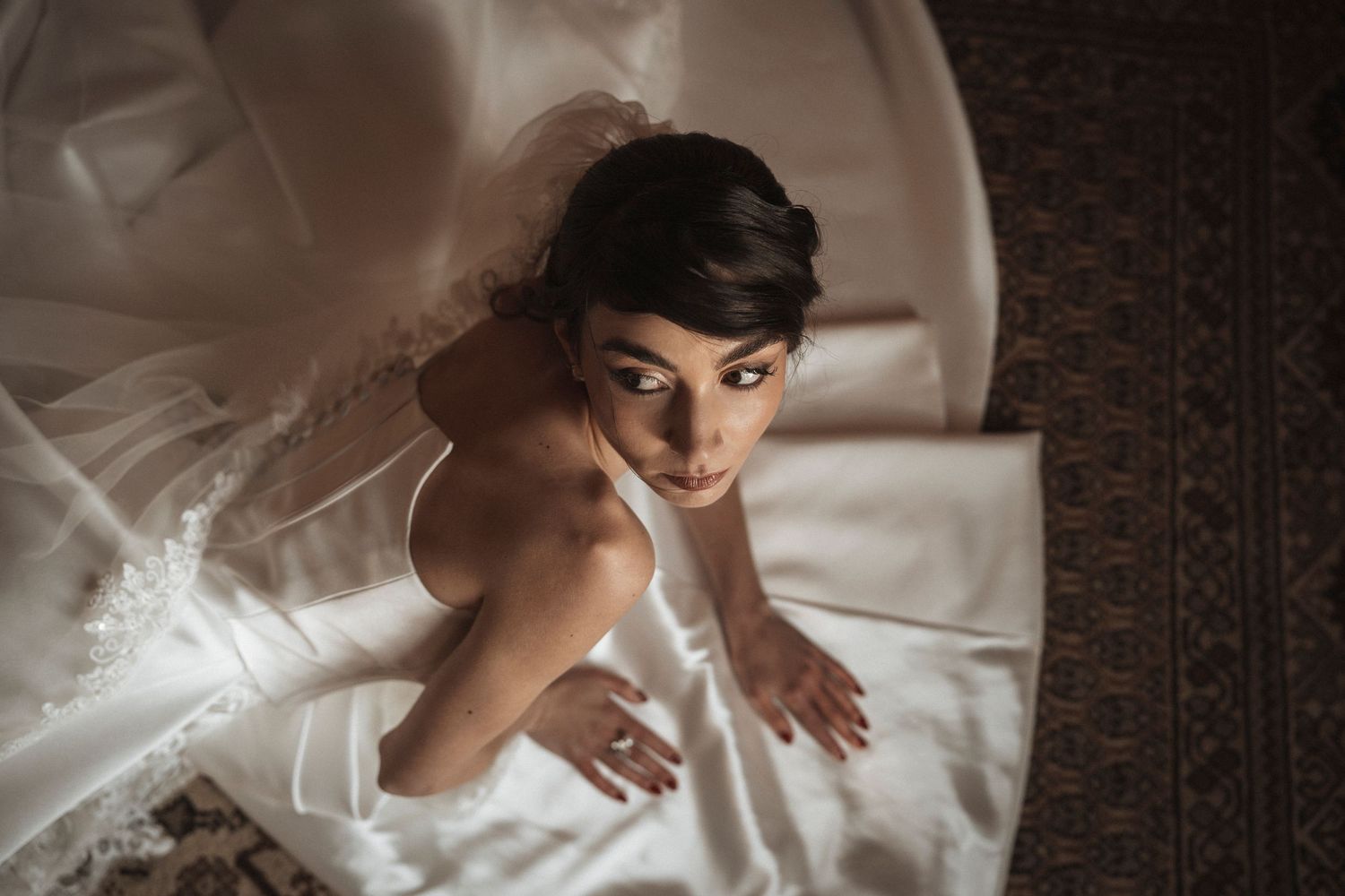 Artistic overhead shot of bride in white dress against textured background.
