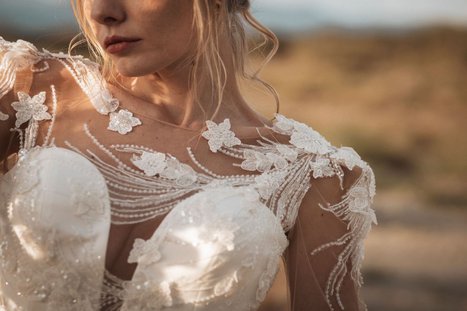 Detailed close-up of intricate white lace and beadwork on wedding dress bodice.