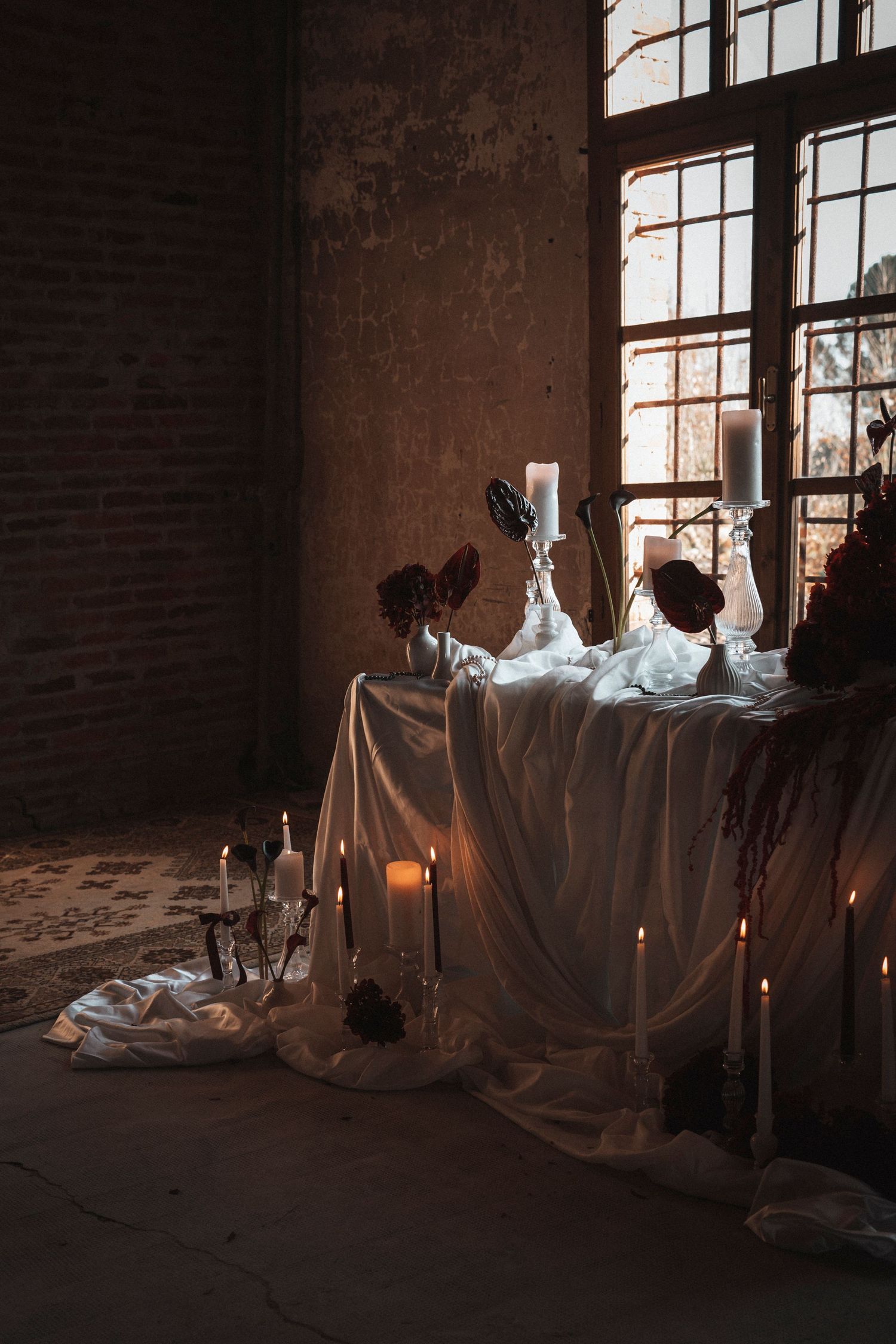 Moody interior scene with white fabric draping and sunlight streaming through industrial windows.