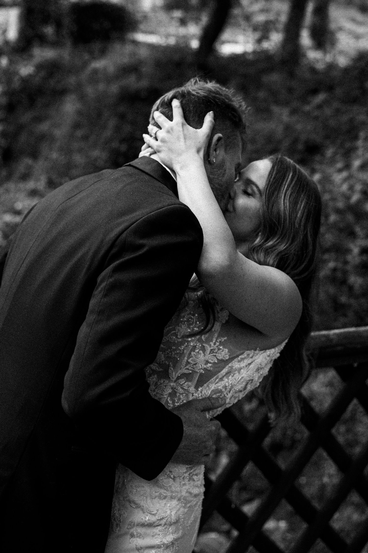 A romantic wedding couple sharing a tender kiss in a natural outdoor setting.