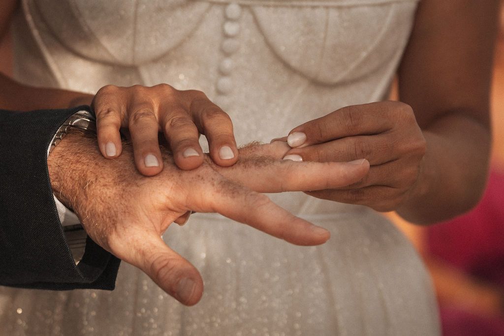 Close-up of hands during a wedding ring exchange ceremony.
