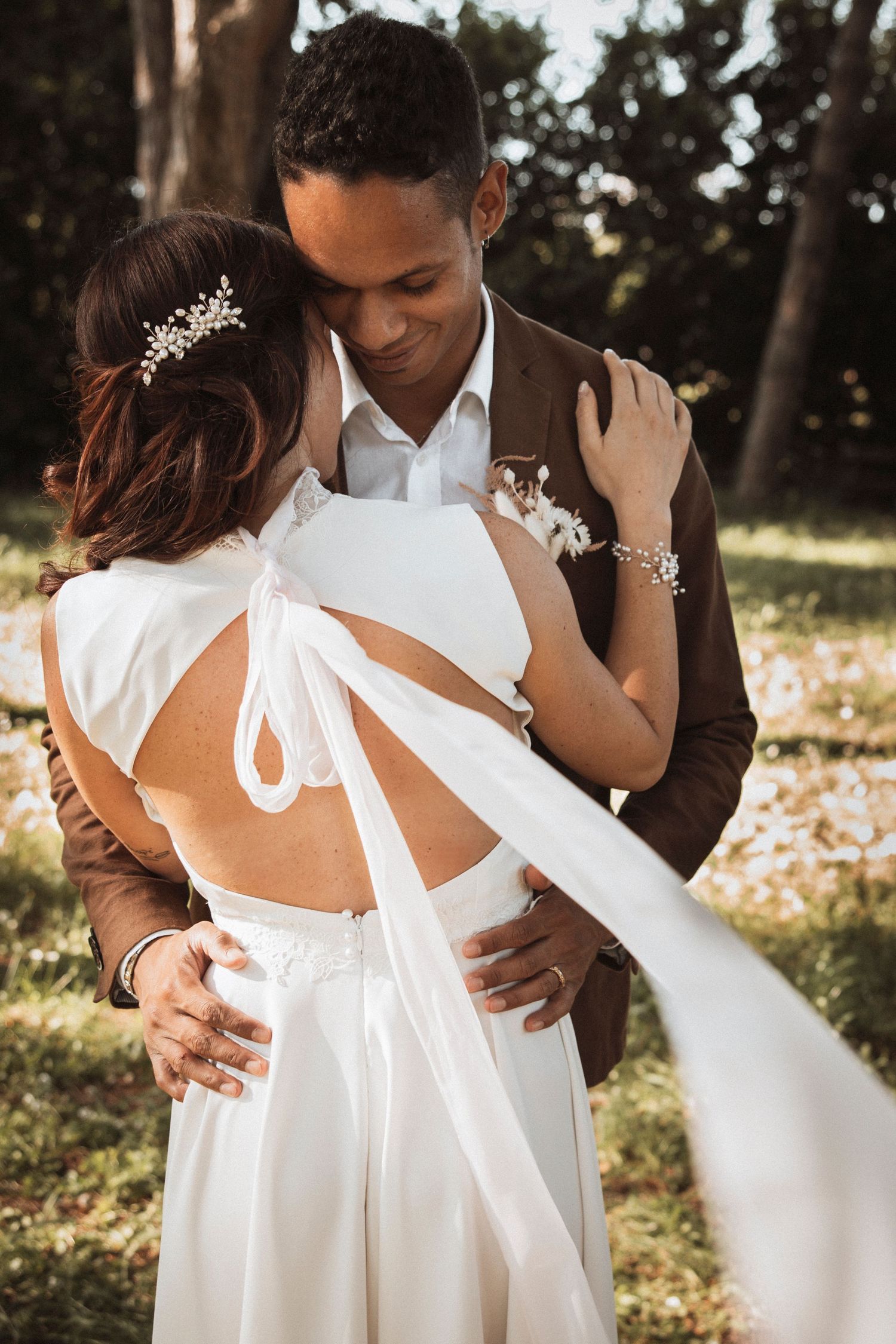Close-up shots of a white wedding dress with tie details in natural sunlight.