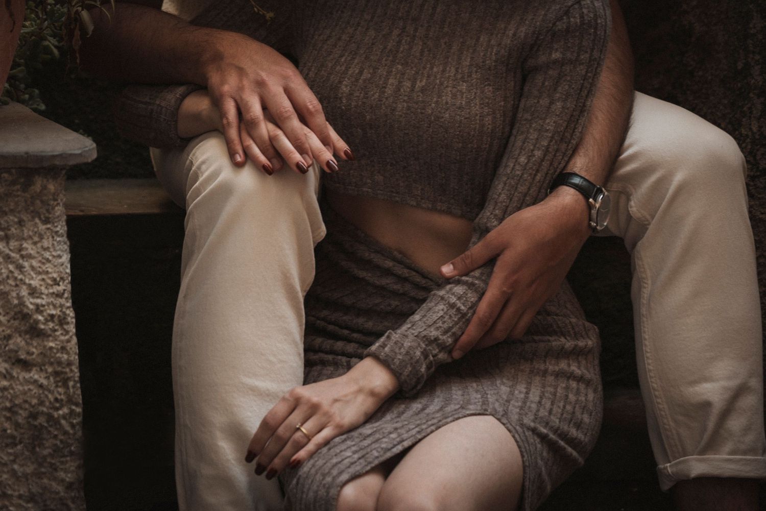 Close-up detail of hands resting on textured fabric furniture.