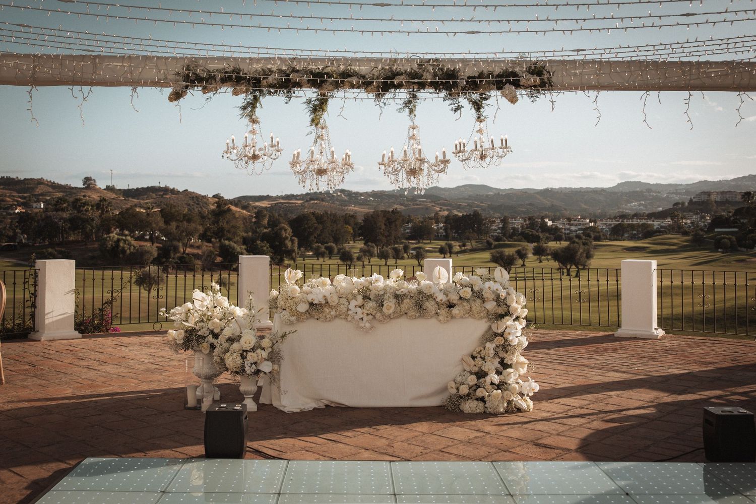 Wedding ceremony space decorated with white floral arrangements and crystal chandeliers.