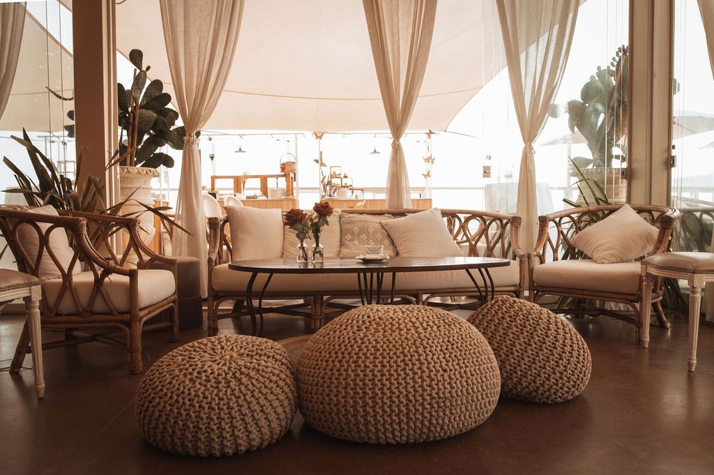 Cozy lounge area with beige curtains and knitted poufs creating an intimate atmosphere.