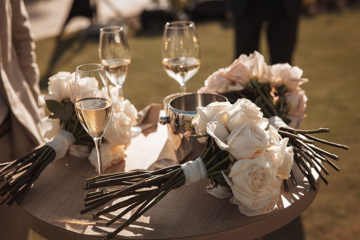 White roses and elegant table settings with wine glasses create a luxurious wedding reception atmosphere.