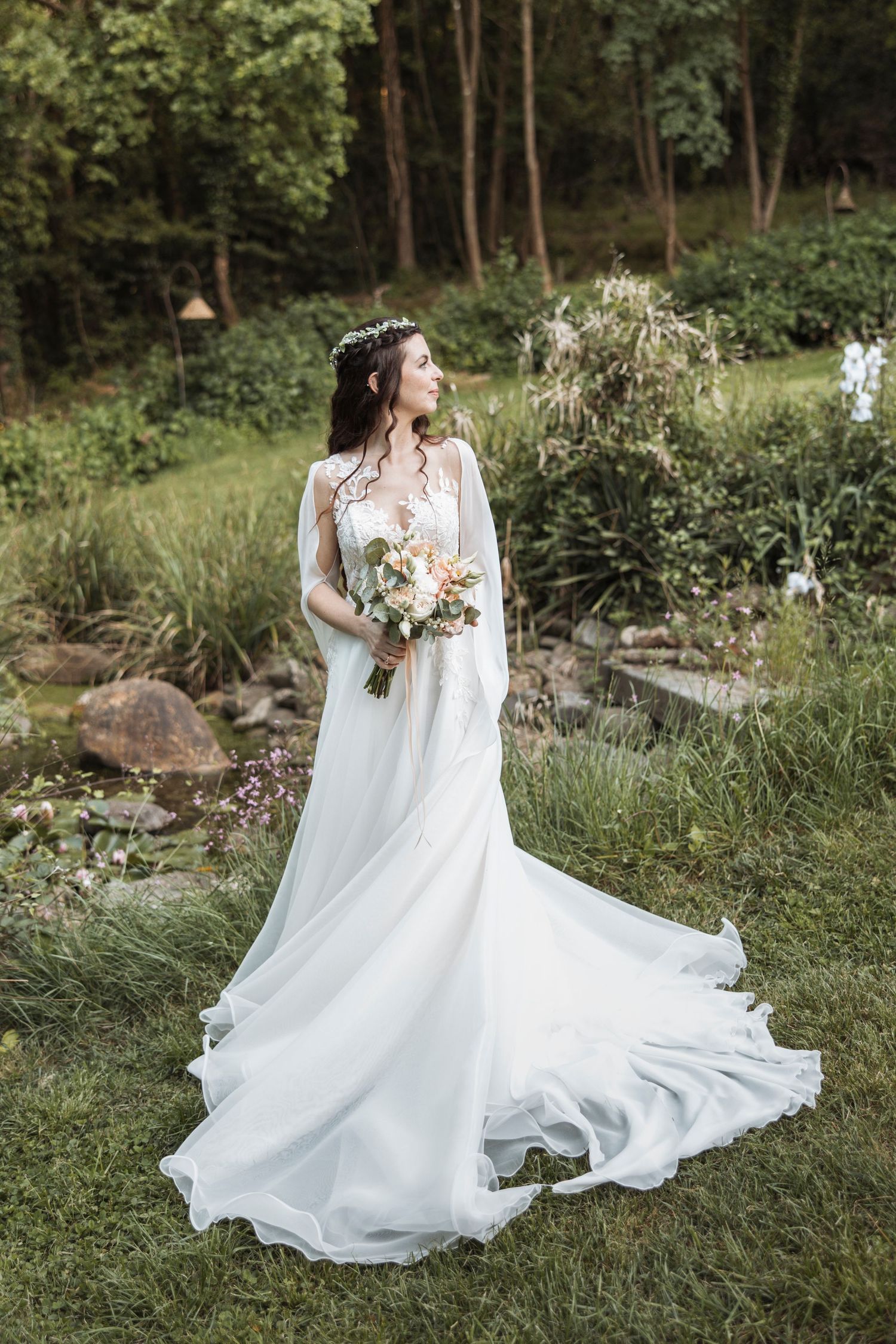 Bride in flowing white dress twirling in garden setting.