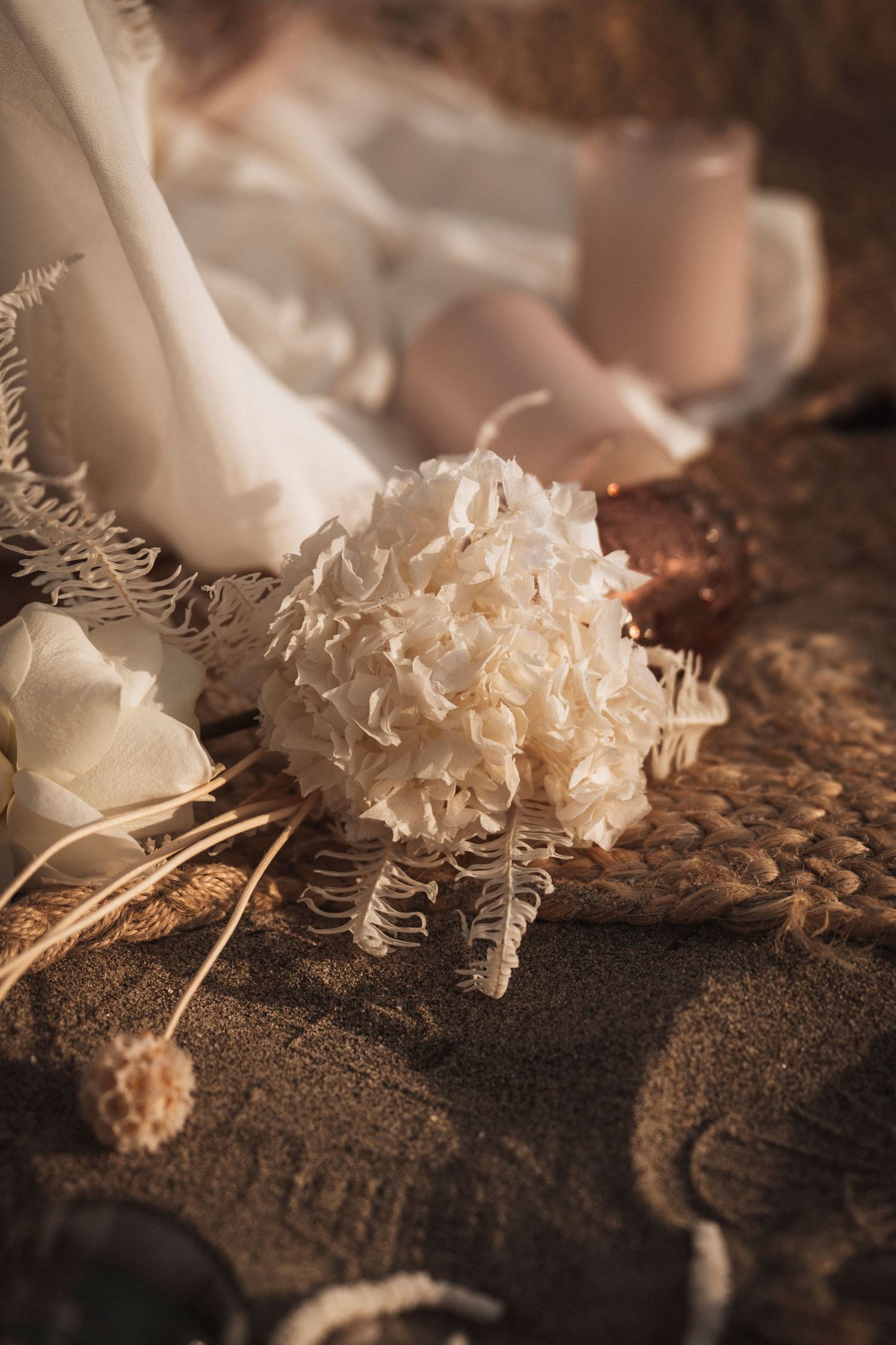 A delicate white hydrangea flower with dried botanical elements in a moody, vintage-style composition.