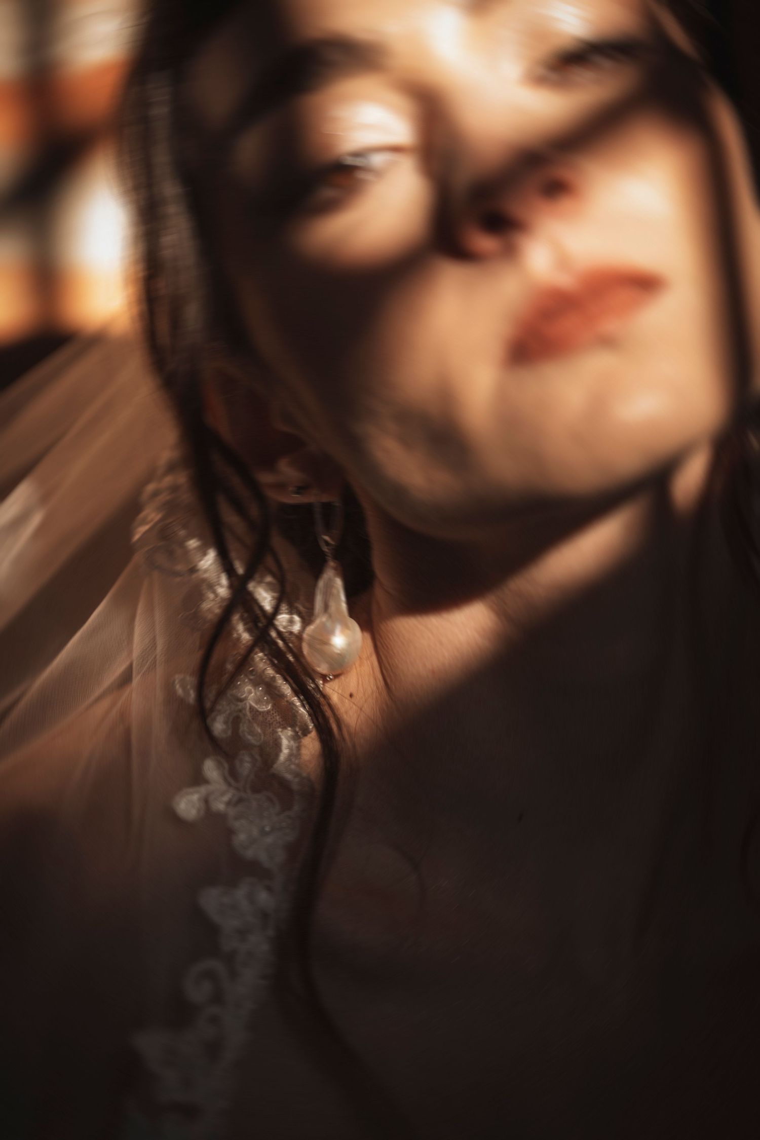 Artistic portrait with soft focus and dramatic shadows creating ethereal mood through window light.