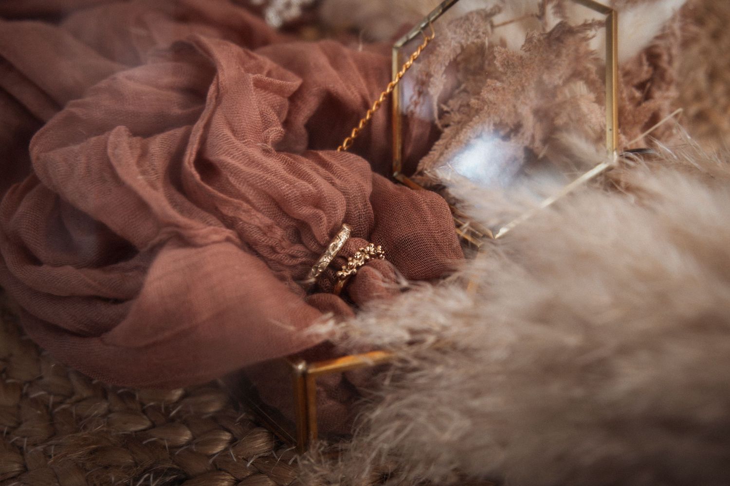 Wedding details featuring pearl accessories and dried flowers on terracotta fabric.