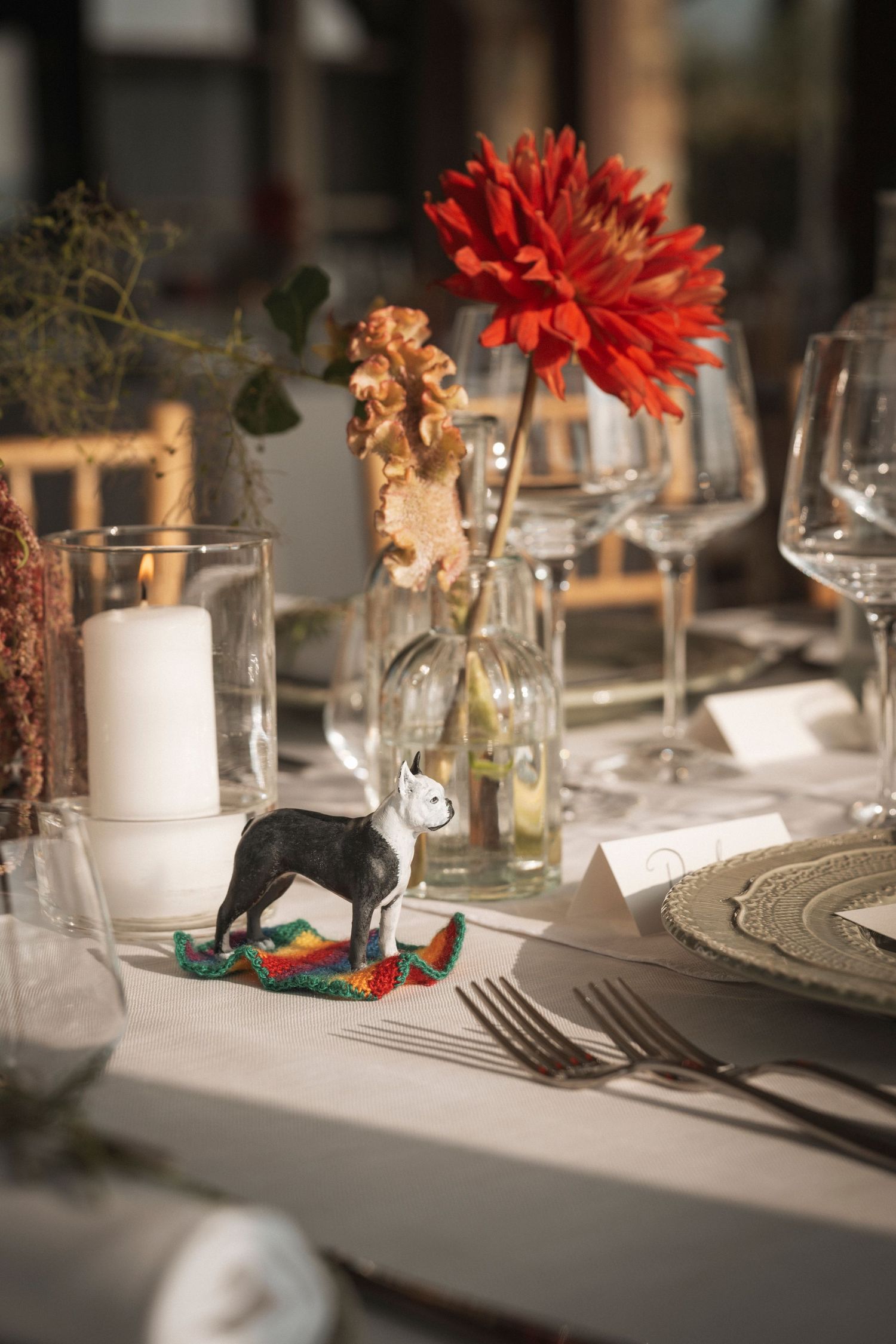 Elegant wedding table setting with red flowers, white candles, and formal place settings.